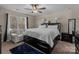 Cozy bedroom with a large black bed frame, a sitting area, and a ceiling fan for optimal comfort at 3181 Helmsley Ct, Concord, NC 28027