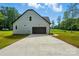 Charming home exterior features a dark garage door, concrete driveway, and blue siding in a landscaped yard at 409 Henry Chapel Rd, Belmont, NC 28012