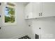 Well-lit laundry room with white cabinets, black and white patterned tile floor, and a window overlooking the yard at 409 Henry Chapel Rd, Belmont, NC 28012