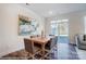 Bright dining room with wooden table, gray upholstered chairs, modern art, and sliding glass doors to the backyard at 4211 Black Ct # 193, Harrisburg, NC 28075