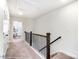 Bright hallway with neutral carpet, dark wood railing, and bedroom doorway at 4211 Black Ct # 193, Harrisburg, NC 28075