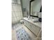 Bright bathroom featuring a framed mirror above a white vanity, complemented by soft, patterned rugs and a shower at 6301 Park South Dr, Charlotte, NC 28210