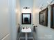Charming powder room features pedestal sink, decorative mirror, and coastal decor at 6301 Park South Dr, Charlotte, NC 28210