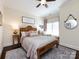 Bedroom with rustic wooden bedframe, ceiling fan, side tables with lamps and light-filled window at 6301 Park South Dr, Charlotte, NC 28210