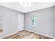 Neutral bedroom with wood-look flooring, white door, trim, and a window at 6628 Cool Water Ct, Charlotte, NC 28215