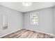 Bright bedroom showcasing a window, light-toned floors, and soft gray walls at 6628 Cool Water Ct, Charlotte, NC 28215