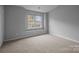 Bright bedroom with neutral carpeting and natural light from a large window at 7707 Petrea Ln, Charlotte, NC 28227