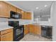 The kitchen features black appliances, wooden cabinets, and tile flooring, with a view into the living room at 7707 Petrea Ln, Charlotte, NC 28227