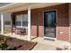 Close-up of a home's brick front porch with white columns, bench seating, and decorative front door at 1017 Village Green Ln, Rock Hill, SC 29730