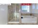 Modern bathroom featuring a glass-enclosed shower and a soaking tub with a window view at 1049 Merganser Way, Indian Trail, NC 28079