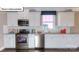 Modern kitchen with white cabinets, stainless steel appliances, and a view of the backyard at 1049 Merganser Way, Indian Trail, NC 28079