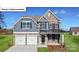 Charming two-story home with stone and blue siding, a three-car garage, and a manicured lawn at 1051 Merganser Way, Indian Trail, NC 28079