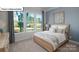 Serene bedroom featuring a comfortable bed, soft lighting, and large windows with an outside view at 1055 Merganser Way, Indian Trail, NC 28079