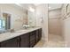 Bathroom features double sinks with granite countertop and walk-in shower with tile surround at 1128 Avalon Pl, Matthews, NC 28104