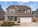 Beautiful two-story home featuring stone veneer, complementary siding, well-maintained landscaping, and a two-car garage at 141 Slip Shot Ln, Troutman, NC 28166