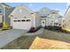 Charming, light blue home featuring an attached two-car garage, landscaped yard, and welcoming front entrance at 14235 Canemeadow Dr # 102, Charlotte, NC 28278