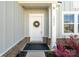 A closer look at the white front door with wreath, vertical address display, and landscaped surroundings at 14235 Canemeadow Dr # 102, Charlotte, NC 28278