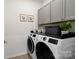 Well-organized laundry room with modern washer and dryer, storage cabinets, and decorative touches at 14235 Canemeadow Dr # 102, Charlotte, NC 28278