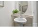 Stylish powder room featuring a pedestal sink, decorative mirror, and neutral color palette at 14235 Canemeadow Dr # 102, Charlotte, NC 28278