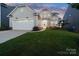 Charming two-story home boasts a manicured lawn, attached garage, and welcoming front porch under an colorful evening sky at 14235 Canemeadow Dr, Charlotte, NC 28278