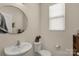 Well-lit bathroom with a round mirror, pedestal sink, and white toilet at 1519 Arcadia Bluff Dr, York, SC 29745