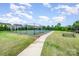 Community tennis court surrounded by lush green grass and mature trees with a walking path and picnic bench at 16200 Winfield Hall Dr, Charlotte, NC 28273