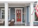 Close-up of the front porch with a vibrant red door, comfortable wicker furniture, and American flag at 21812 Chapel Way # 20, Cornelius, NC 28031