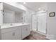 Bright bathroom featuring double sinks and a large shower with glass doors and wood-look floors at 2766 Sherrills Stream Dr, Sherrills Ford, NC 28673
