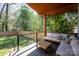 Covered patio with wooden furniture, pillows, privacy fence, and cable railing overlooking large backyard at 3020 Georgia Ave, Charlotte, NC 28205