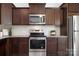 Modern kitchen featuring stainless steel appliances, dark wood cabinets, granite countertops, and tile backsplash at 314 Contentment Dr # 192B, Locust, NC 28097