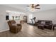 Open-concept living room with hardwood floors, neutral paint, ceiling fan, and comfortable seating area at 4917 Spruce Peak Rd, Charlotte, NC 28278