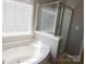 Bathroom featuring soaking tub and glass-enclosed shower with window at 513 Buttercup Way, Fort Mill, SC 29715