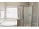Bright bathroom featuring soaking tub and glass-enclosed shower with window at 513 Buttercup Way, Fort Mill, SC 29715