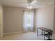 Neutral bedroom featuring a ceiling fan and a compact desk, bathed in natural light at 513 Buttercup Way, Fort Mill, SC 29715
