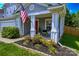 A cozy front porch area with seating for two, lovely landscaping, and an American flag at 513 Buttercup Way, Fort Mill, SC 29715