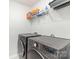 Modern laundry room with front loading gray washer and dryer and overhead shelving at 6048 Chelsea Oaks Rdg, Tega Cay, SC 29708