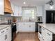 Updated kitchen showcasing bright cabinets, a wood range hood, stainless appliances, and stone countertops at 7417 Shadowlake Dr, Charlotte, NC 28226