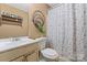 Cozy bathroom featuring a toilet, sink, decorative shower curtain, and towel rack at 8220 Terra Linda Ln, Charlotte, NC 28215