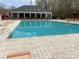 Community pool with an adjacent clubhouse, pergola, tanning chairs, and lounge seating at 9220 Pinaceal Ct, Charlotte, NC 28215