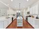 Modern kitchen with white cabinets, stainless appliances, kitchen island with seating, and hardwood floors at 9895 Travertine Trl, Davidson, NC 28036