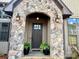 Inviting stone archway frames the front door, enhanced by outdoor lighting and potted ferns for added curb appeal at 1021 Mccollum Oaks Ln, Monroe, NC 28110