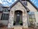 Inviting stone archway frames the front door, enhanced by outdoor lighting and potted ferns for added curb appeal at 1021 Mccollum Oaks Ln, Monroe, NC 28110