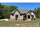 Beautiful exterior of home with stone accents, brown trim, lovely landscaping, and a manicured lawn at 1021 Mccollum Oaks Ln, Monroe, NC 28110