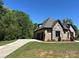 Side view of the house showing the driveway and garage, with stone and brick accents and mature landscaping at 1021 Mccollum Oaks Ln, Monroe, NC 28110