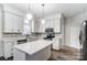 Bright kitchen features white cabinets, stainless steel appliances, gray backsplash, and a center island at 10434 Henbane Ct, Charlotte, NC 28213