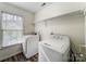 Bright laundry room with a window, washer, dryer, overhead shelf, and clean white walls at 10434 Henbane Ct, Charlotte, NC 28213