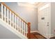 Staircase and entryway with wooden rail, carpeted stairs, and decorative front door at 10810 Kemptown N Sq, Mint Hill, NC 28227