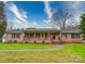 Charming brick home featuring a welcoming front porch and well-maintained lawn at 1115 Kelly Rd, Mount Holly, NC 28120
