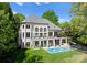 Stunning rear exterior featuring a pool, patio, and manicured lawn with a charming two-story balcony at 12014 James Jack Ln, Charlotte, NC 28277