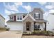 Charming two-story home with a mix of siding and stone accents, with an attached two car garage and manicured lawn at 129 Doncaster Dr, Mooresville, NC 28115